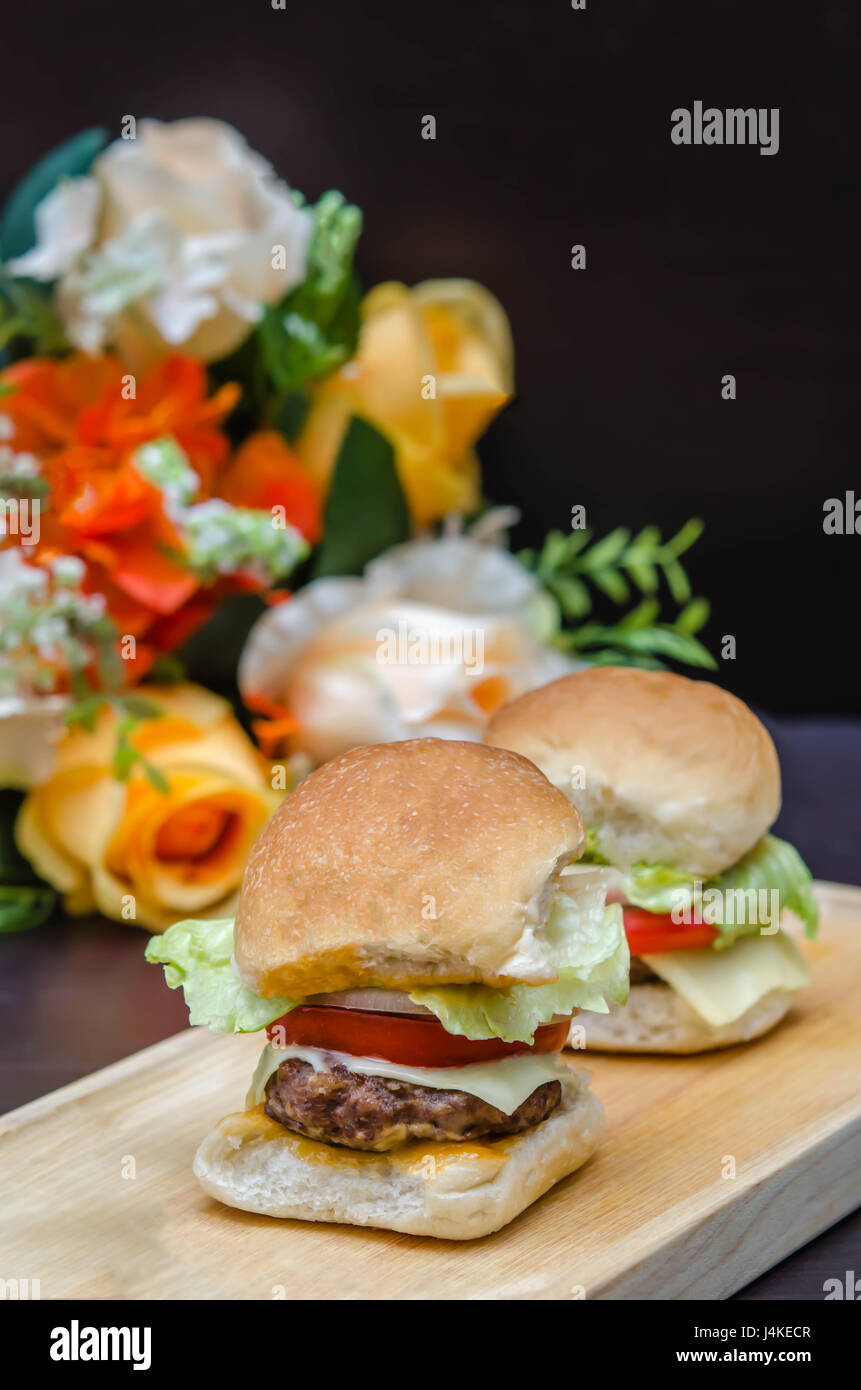 Köstlichen hausgemachten Gourmet-Käse Burger vom Rind mit frischen Zutaten, die auf hölzernen Platten gelegt Stockfoto