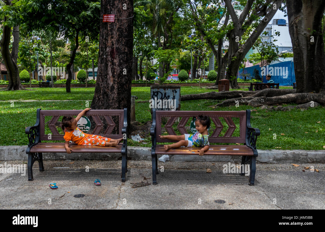 Zwei kleine Kinder spielen auf den Bänken im Park in Saigon Vietnam Stockfoto