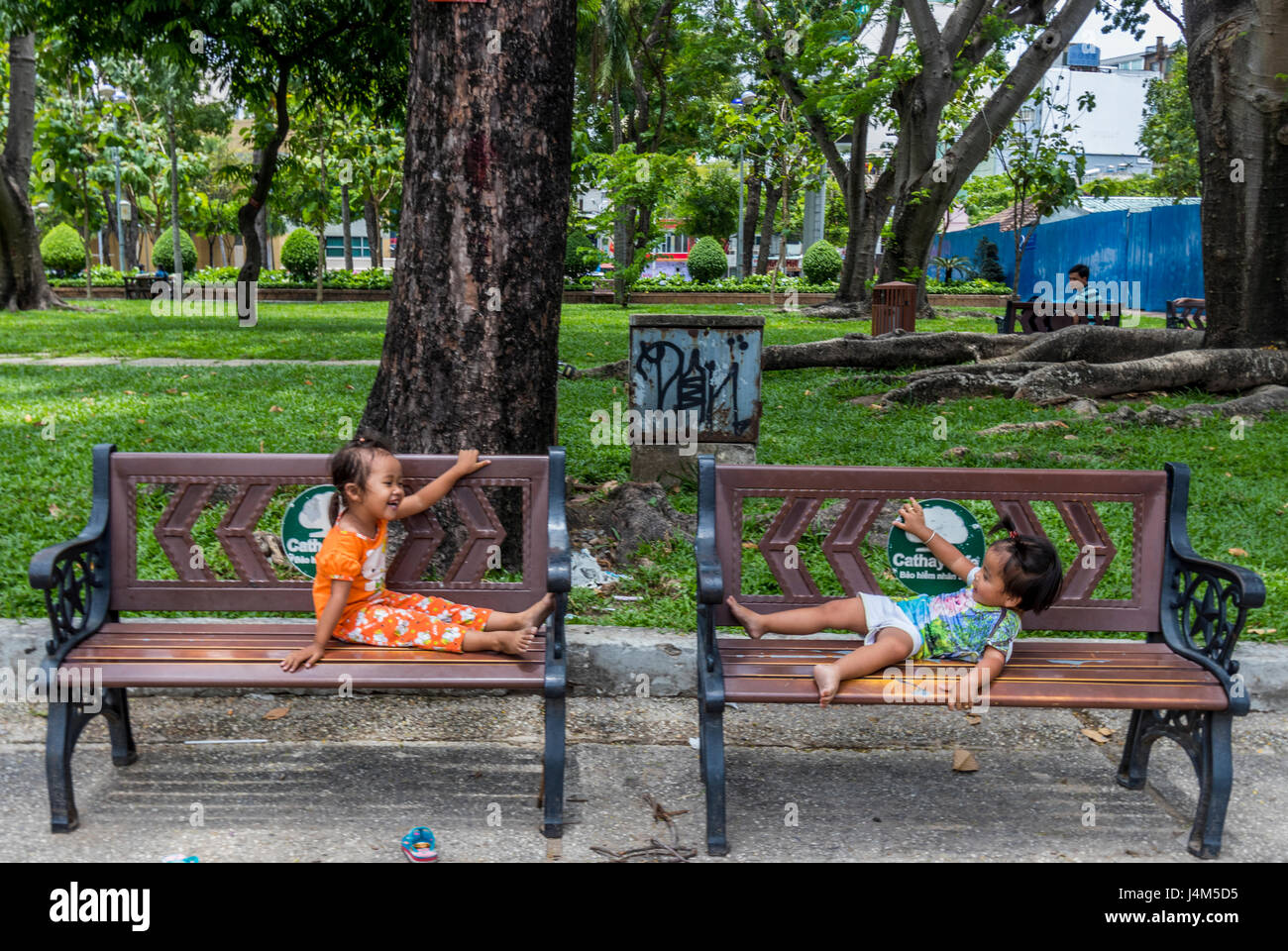 Zwei kleine Kinder spielen auf den Bänken im Park in Saigon Vietnam Stockfoto