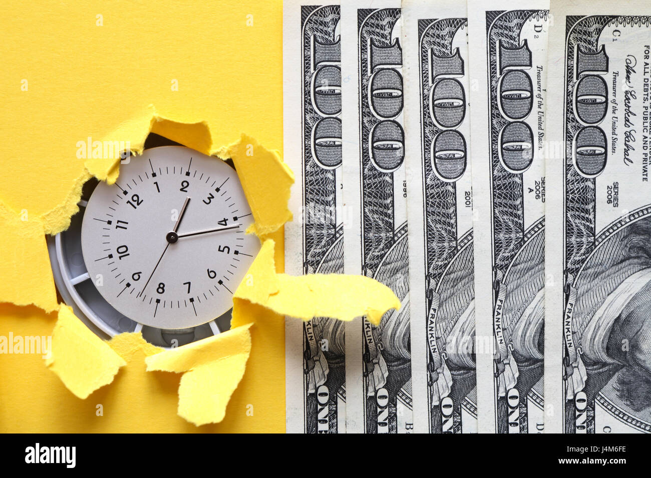 Zeit ist Geld. Uhr in Loch in gelbem Papier in der Nähe von hundert-Dollar-Banknoten Stockfoto