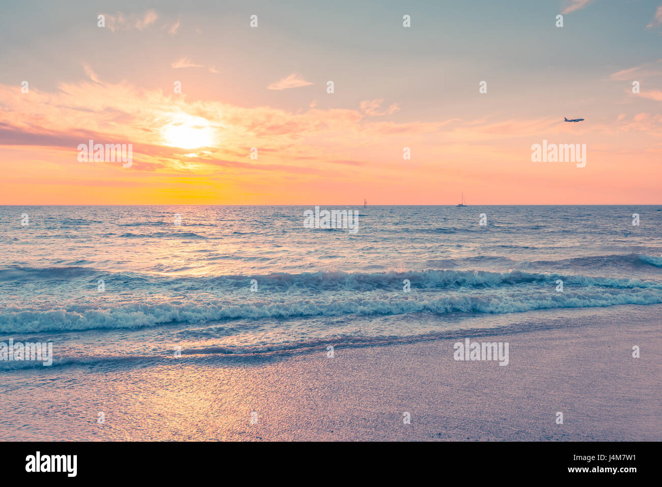Wellen bei Sonnenuntergang mit Schiff und Flugzeug auf Hintergrund an einem warmen Abend, südaustralische Küste. Pastelligen Farbtöne. Stockfoto