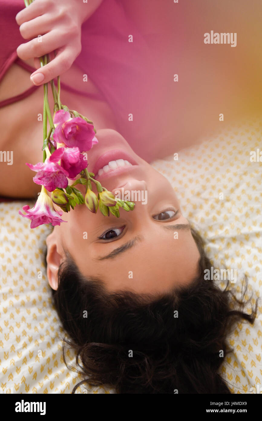 Hispanic Frau auf Bett mit Blumen Stockfoto