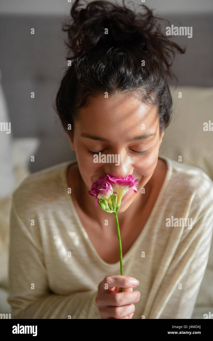 Hispanic Woman riechende Blume Stockfoto