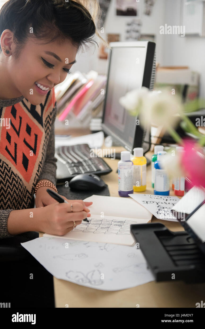 Gemischte Rennen Frau sitzt in der Nähe von Computer-Zeichnung auf Papier Stockfoto