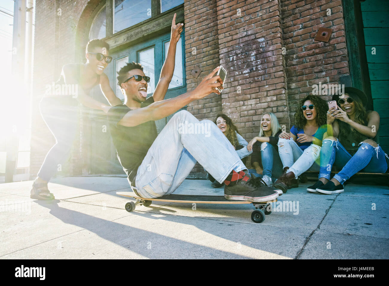 Frau Freund sitzen auf Skateboard in Stadt schieben Stockfoto