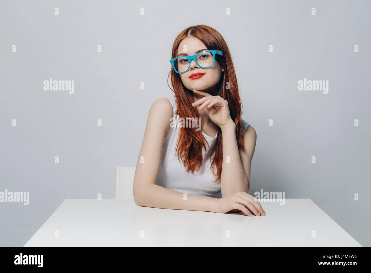 Nachdenklich kaukasischen Frau sitzt am Tisch tragen blaue Brillen Stockfoto