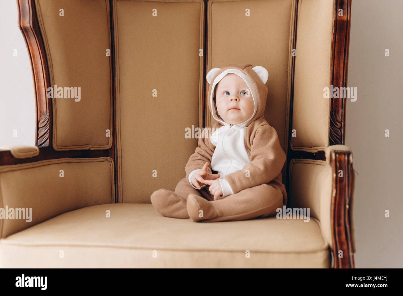 Kaukasische Baby Junge sitzt im Sessel tragen Bär Kostüm Stockfoto