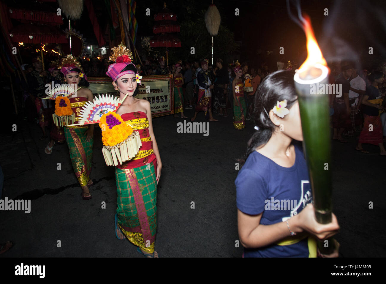 Bali-Mädchen tragen Fackeln während der feierlichen Prozession in die Ngrupuk parade für balinesische Neujahr. Straßenparade der balinesischen Kultur Stockfoto