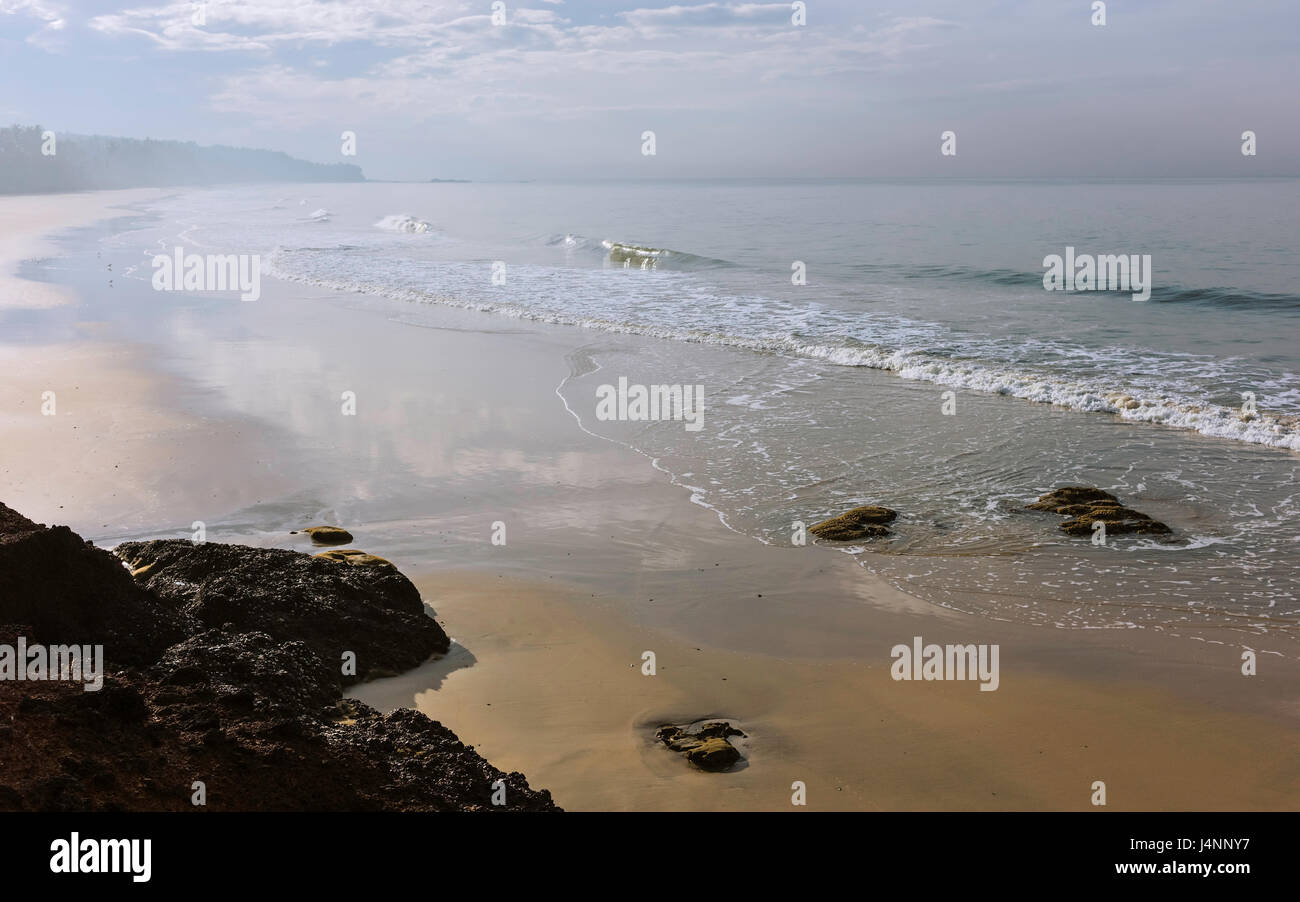 Dawn Nebel hebt sich über den schönen Sandstrand bei Ebbe mit dem arabischen Meer an einem feinen Wintermorgen in der Nähe von Thottada Dorf, Kannur, Kerala, Indien. Stockfoto