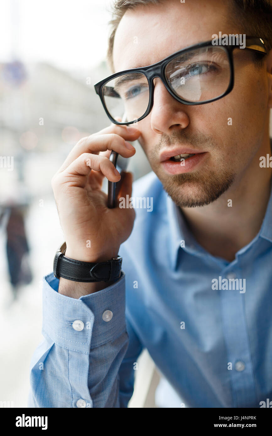 Porträt der jungen Unternehmer tragen große schwarze Brille diskutieren Arbeit sprechen mit dem Handy am Fenster im café Stockfoto