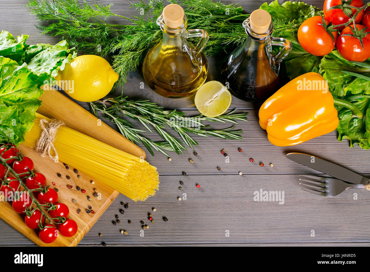 Spaghetti, Cherry Tomaten, Olivenöl, Kräuter und Gewürze auf alten grauen Hintergrund aus Holz. Legen Sie für gesunde Lebensmittel. Zutaten für Salat Stockfoto