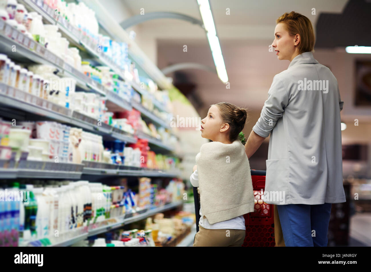Porträt der erwachsenen Frau mit kleinen Mädchen, die Wahl der Lebensmittel zu kaufen im Supermarkt einkaufen Stockfoto