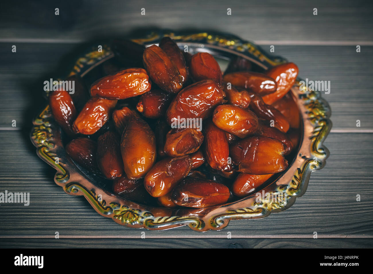 Schöner Hintergrund mit getrocknete Datteln auf einem silbernen Tablett auf hölzernen Hintergrund. Das muslimische Opferfest des Heiligen Monats Ramadan Kareem. Freiraum für Ihre Stockfoto