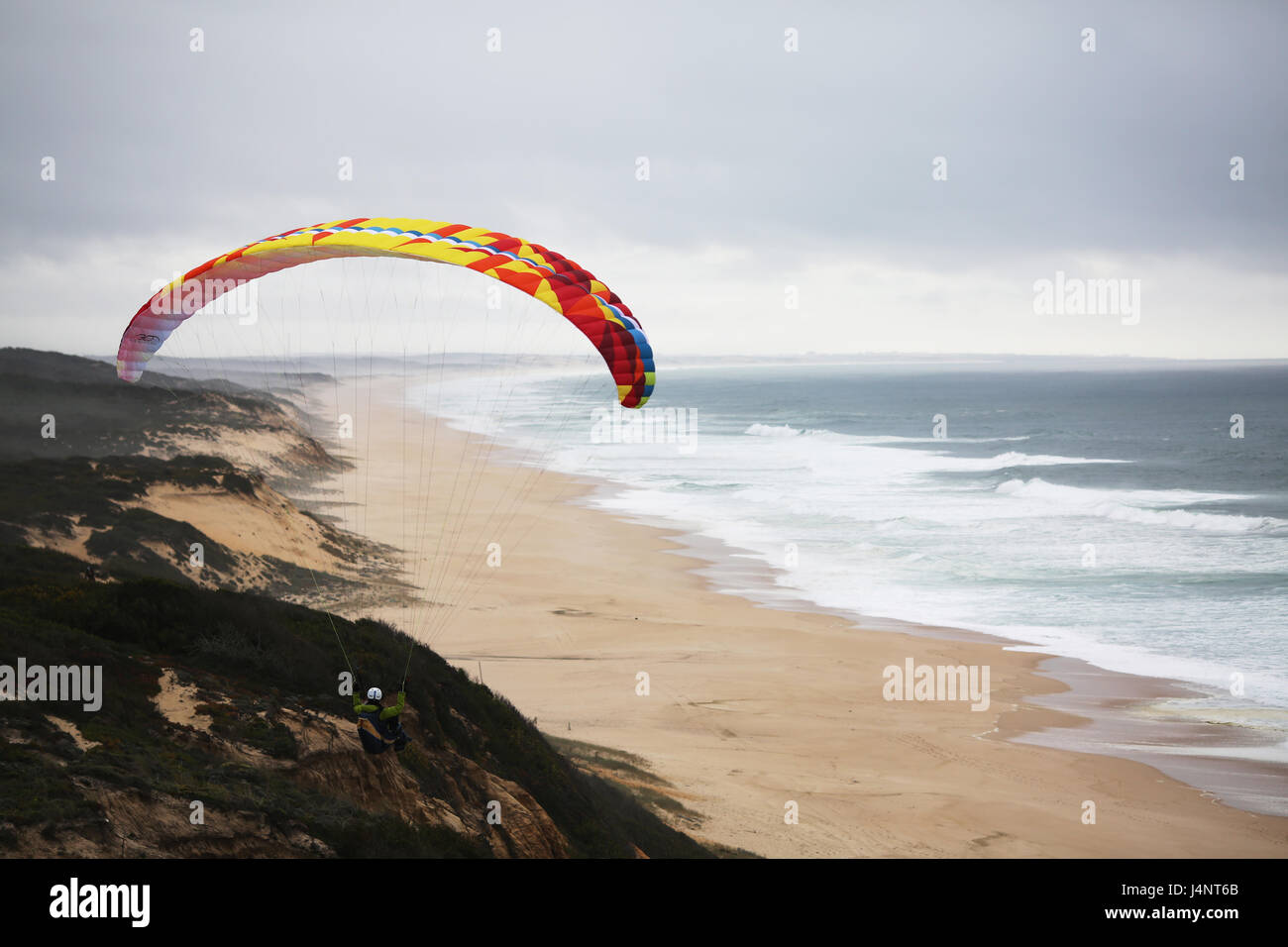 Eine weibliche Gleitschirmpilot soaring Aberta Nova Beach. Stockfoto