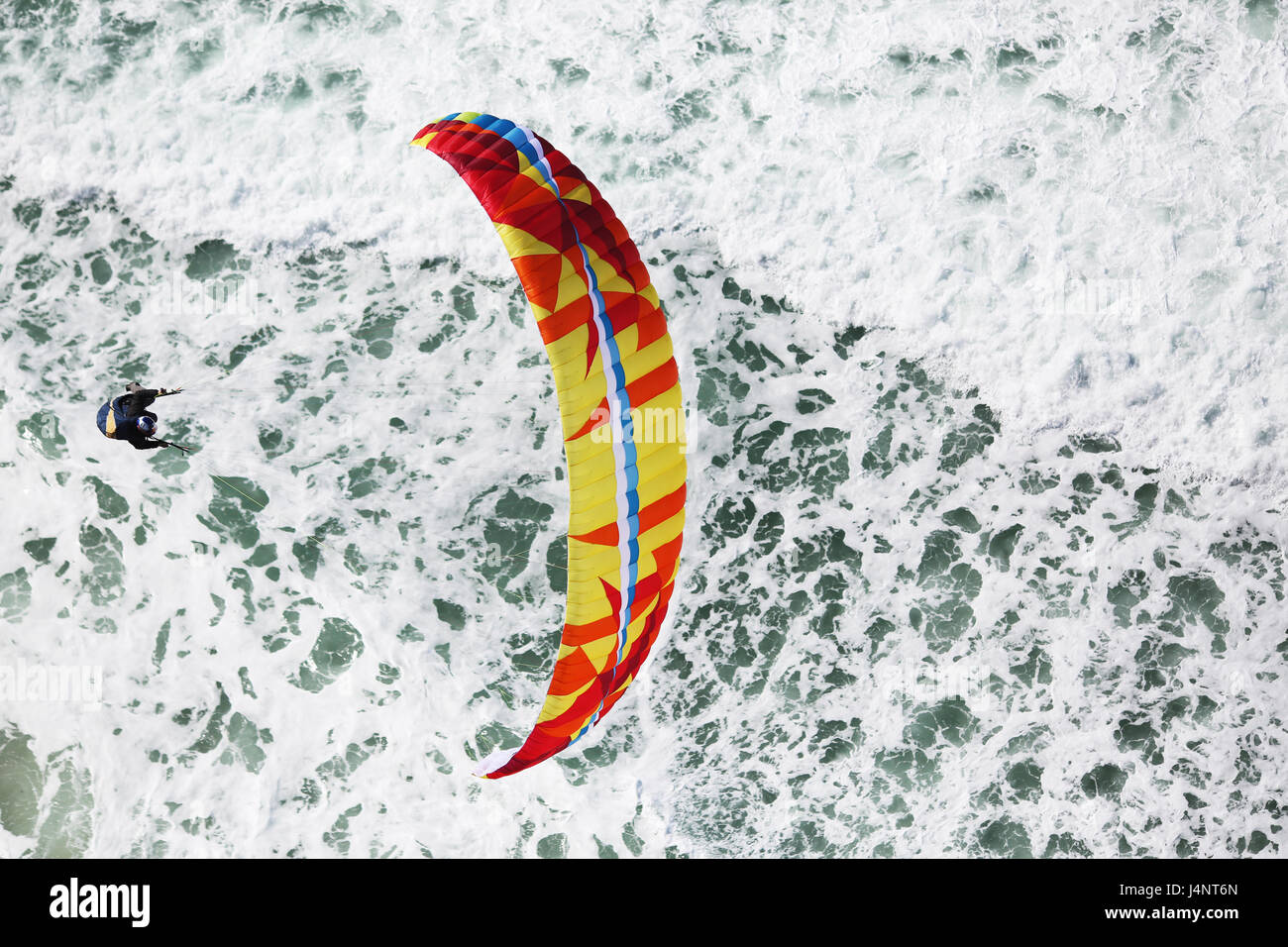 Eine Gleitschirmpilot fliegt über den brechenden Wellen am Strand von Bicas, Portugal. Stockfoto