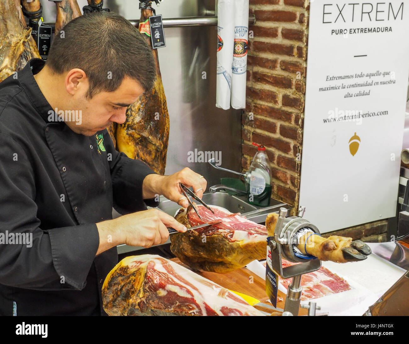 Eine Europäische kaukasischen Mann unten in Scheiben schneiden Spezialität de Serrano Jamon Iberico Schinken Bein zentralen Markt Mercado Central Valencia Stockfoto