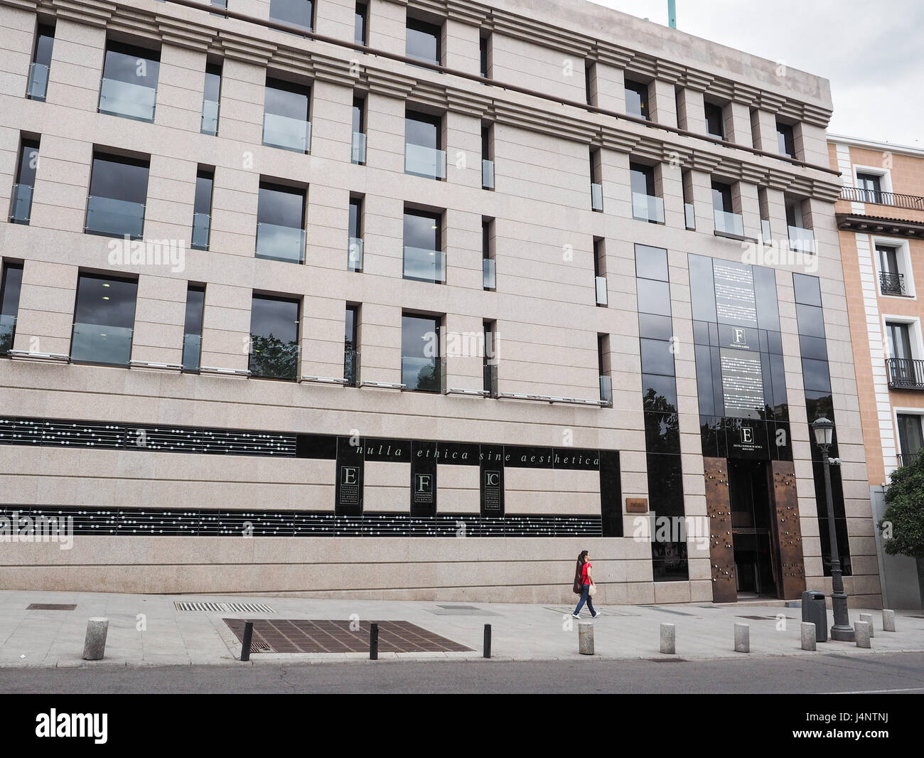 Musikschule Escuela Superior de Musica Reina Sofia mit einer jungen Dame Frau Fußgängerzone in Rot zu Fuß vorbei an allein, Madrid Spanien Stockfoto