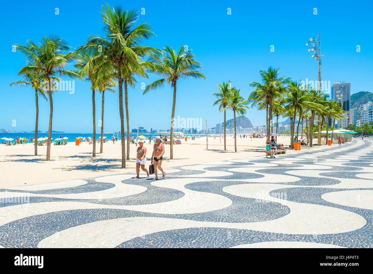 RIO DE JANEIRO - 15. Februar 2017: Ein paar gehen gemeinsam entlang der ikonischen schwarz-weiß Wellenmuster der Promenade am Strand Copacabana. Stockfoto