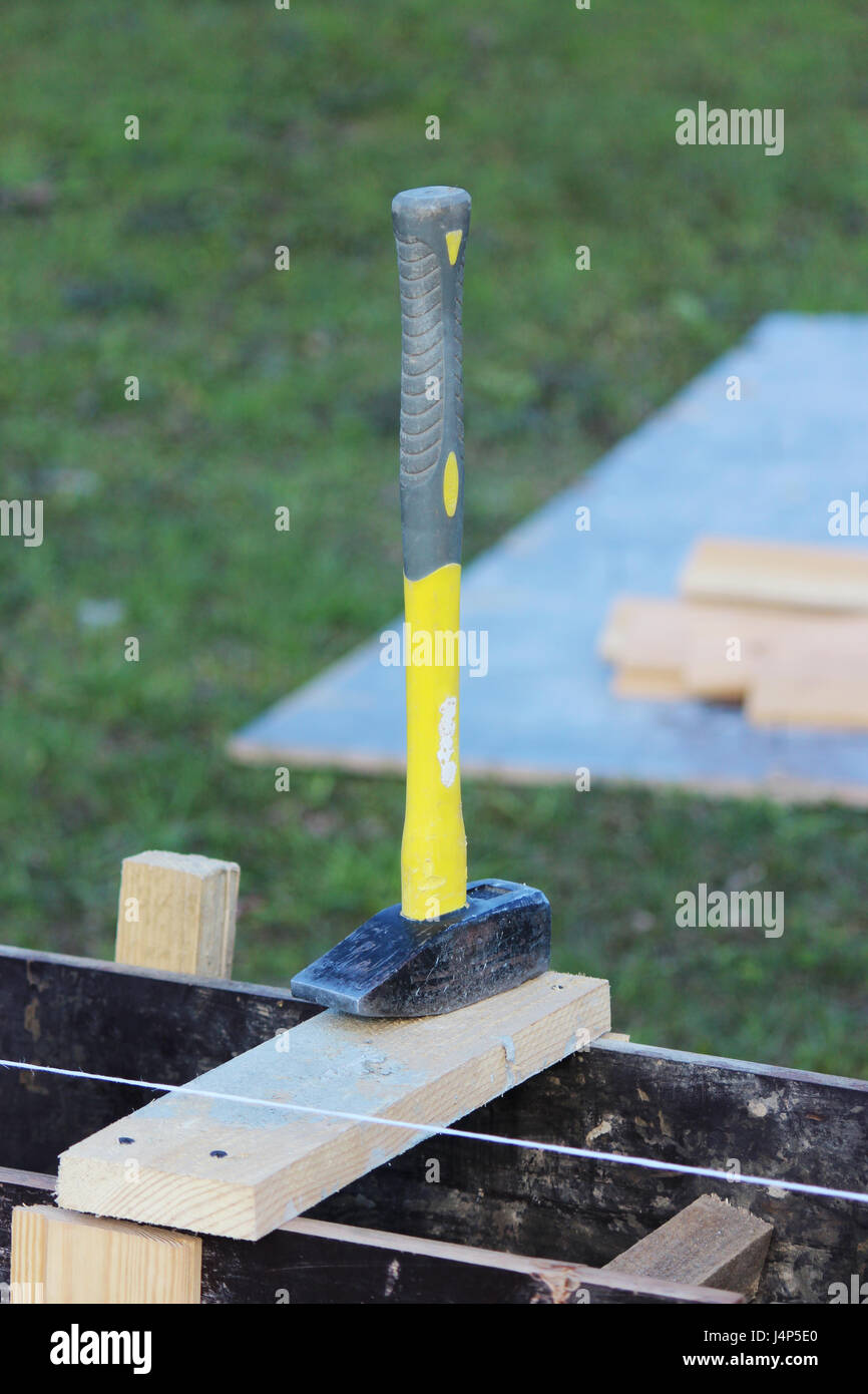 Bau-Werkzeug-Hammer mit einem gelben Griff liegt auf der Schalung Stockfoto