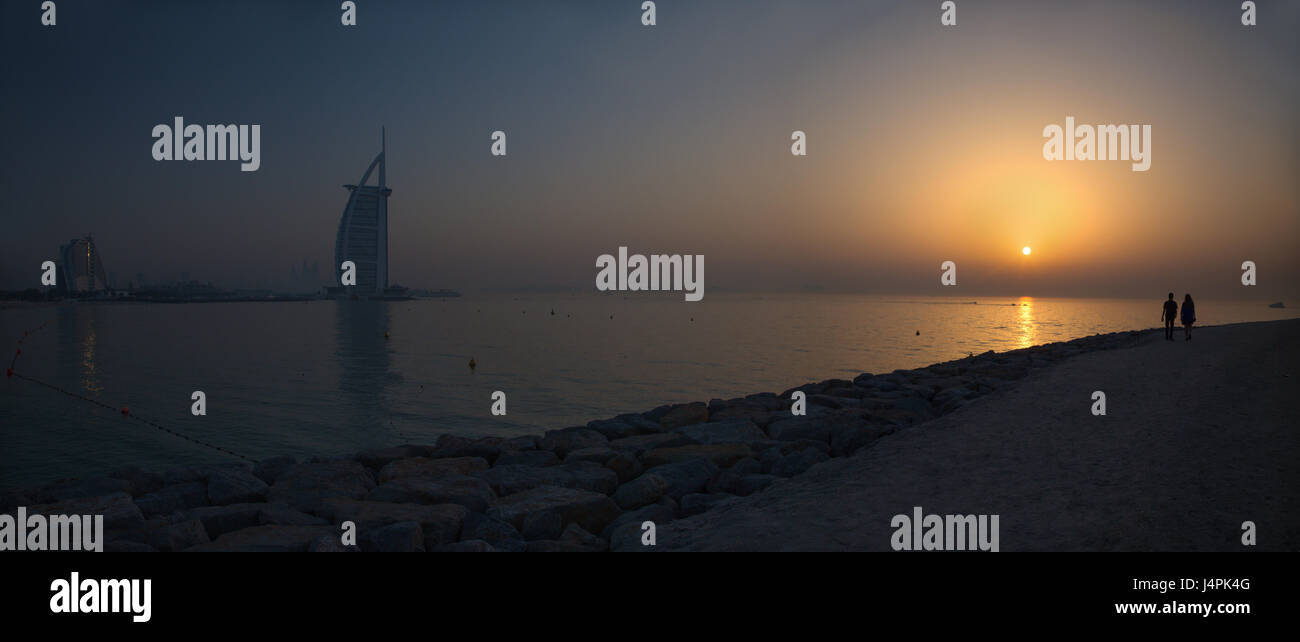 DUBAI, Vereinigte Arabische Emirate - 30. März 2017: Der Abend Silhouette mit dem Burj al Arab und Jumeirah Beach Hotels und das Paar auf dem Weg. Stockfoto