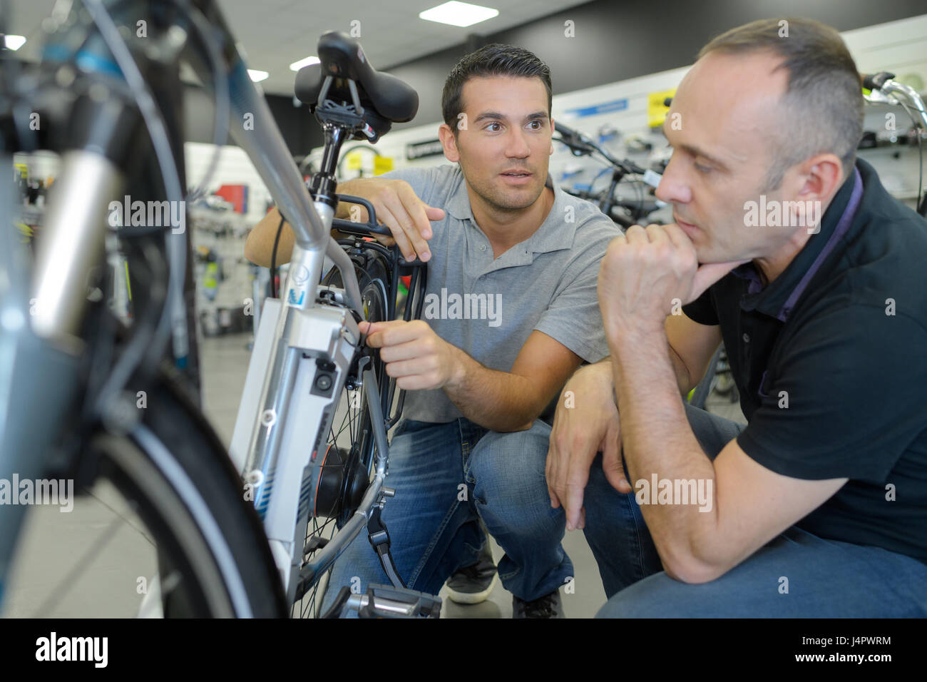 Mann-Kunde und Verkäufer diskutieren Fahrrad Aufführungen im Fahrradladen Stockfoto