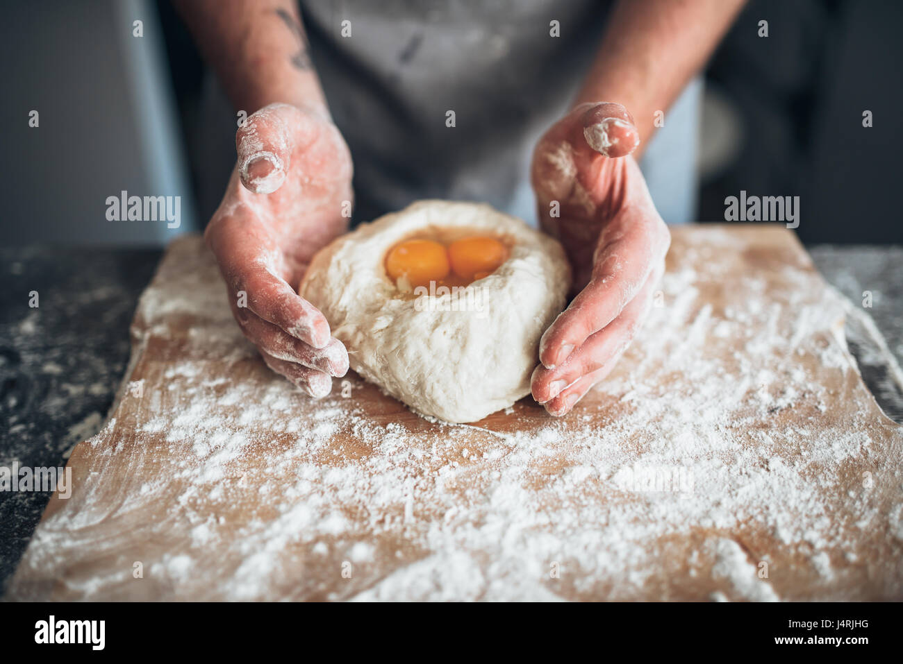 Männliche Bäcker Händen vermischen den Teig mit Ei. Brot-Vorbereitung. Hausgemachte Backwaren Stockfoto