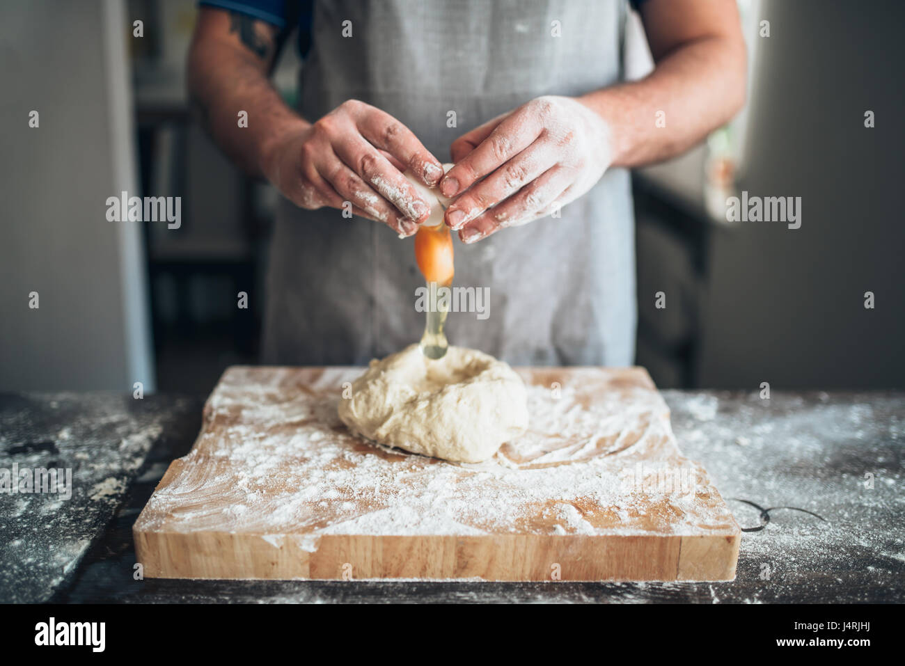 Koch Händen vermischen den Teig mit Ei. Brot-Vorbereitung. Hausgemachte Backwaren Stockfoto