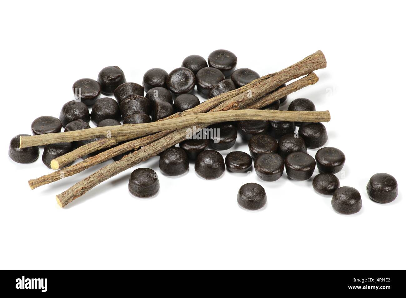 Lakritz-Bonbons mit getrockneten Stangen Süßholzwurzel isoliert auf weißem Hintergrund Stockfoto