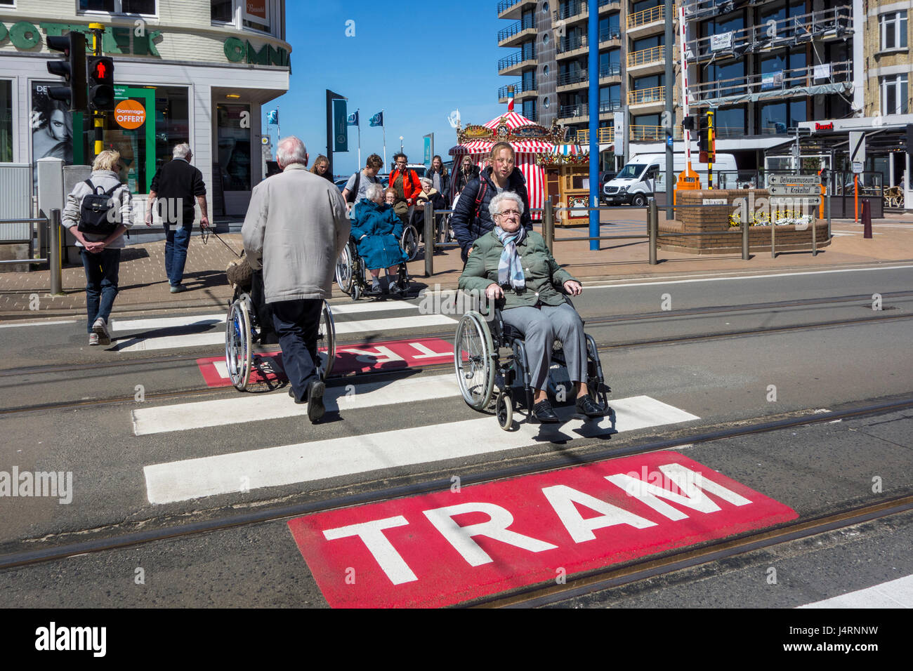 Gruppe der älteren Behinderten im Rollstuhl durchqueren Straße über Fußgängerüberweg / Zebrastreifen in der Stadt Stockfoto
