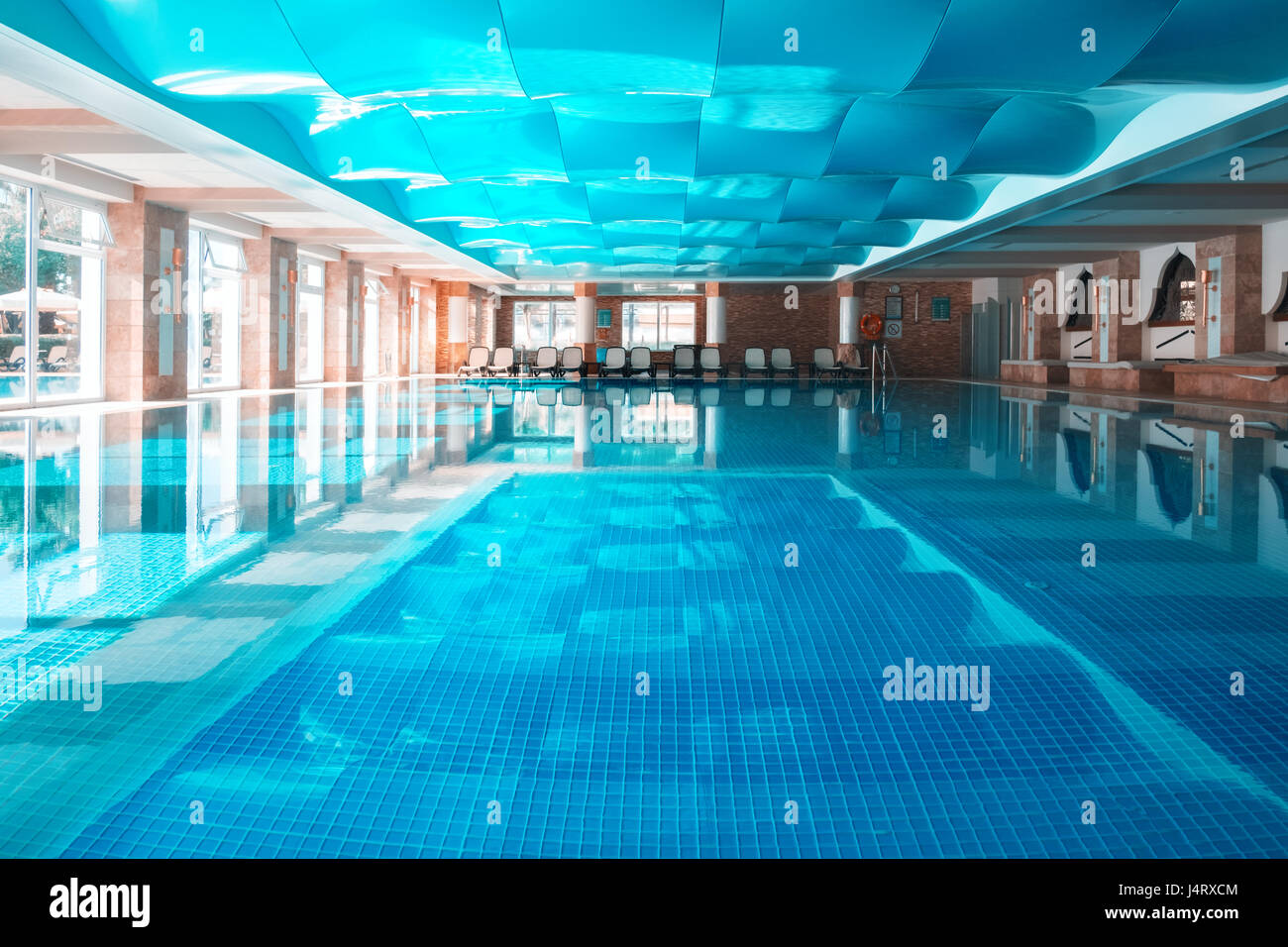 Nachauftragnehmer Schwimmbad mit blauen wellenförmigen Dach. Klares Wasser und ruhigen Oberfläche Stockfoto