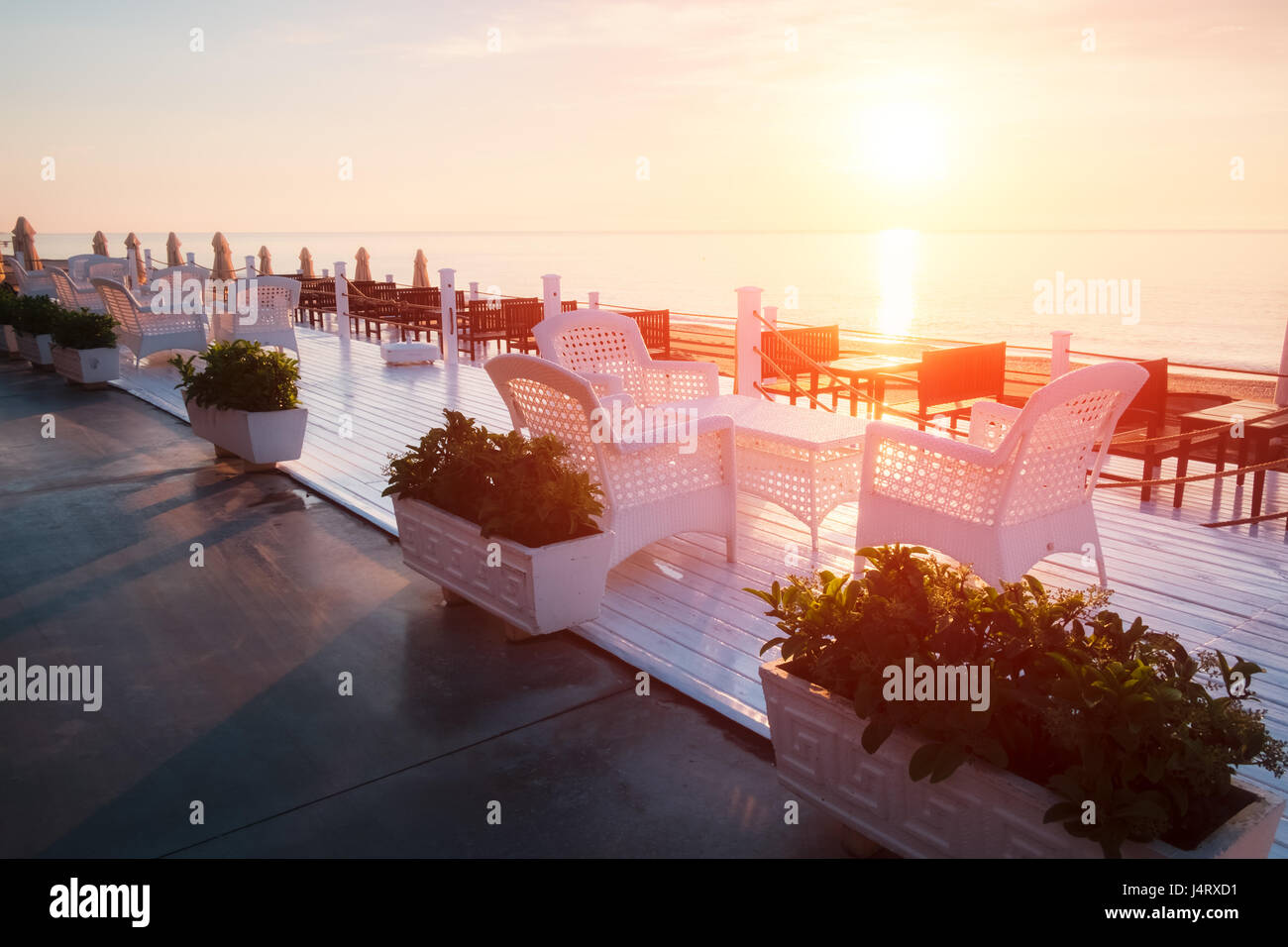 Sommer-Restaurant am Strand. Atemberaubenden Blick auf das Mittelmeer. Weiße Holzterrasse und geflochtene Möbel Stockfoto