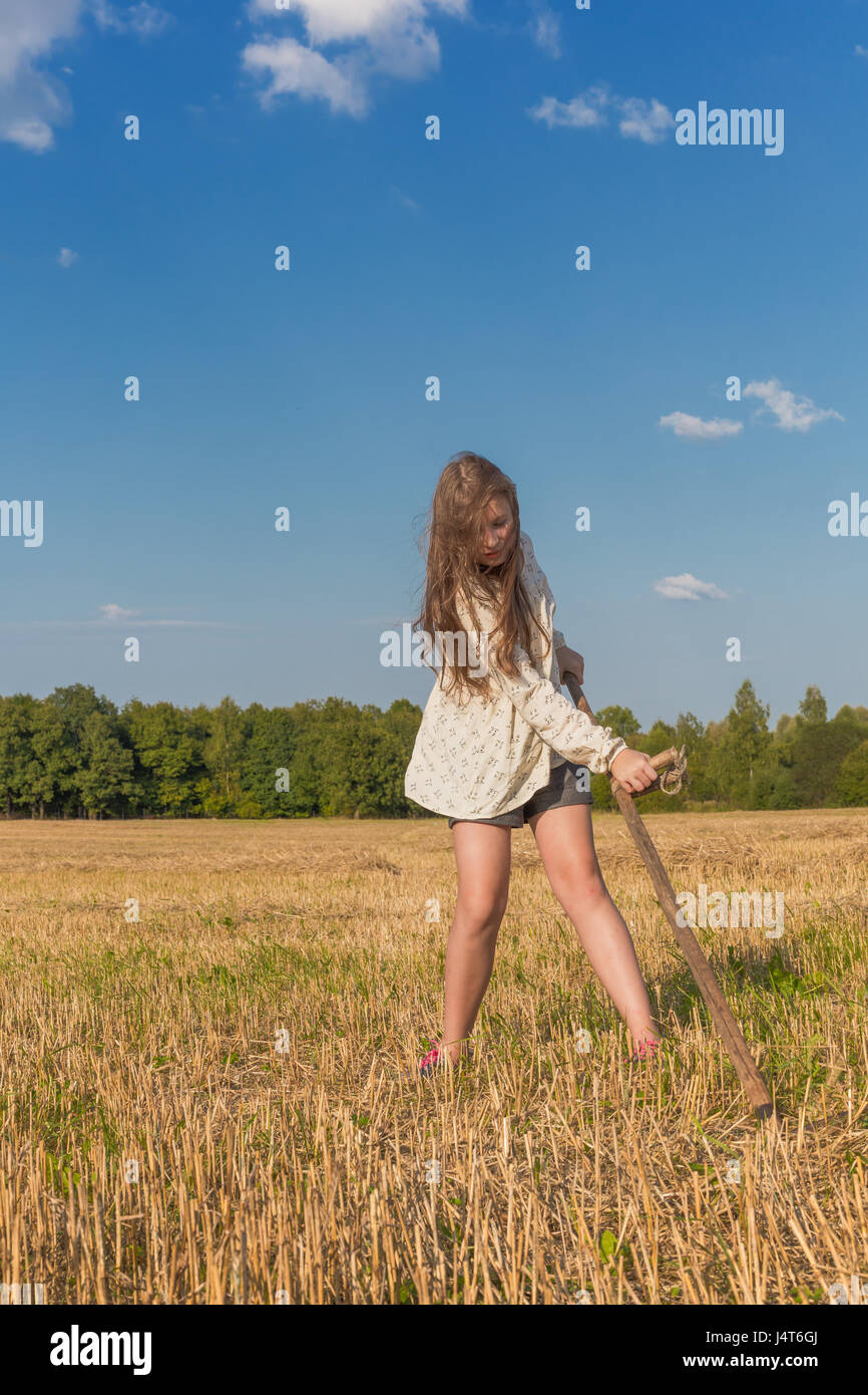 Teengirl mit einer Sense im Sommer Bereich traditionelle Bäuerin Stockfoto