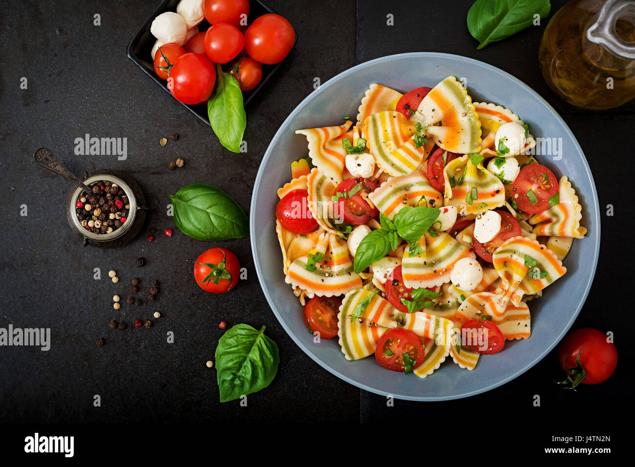 Nudeln, bunte Farfalle-Salat mit Tomaten, Mozzarella und Basilikum. Stockfoto