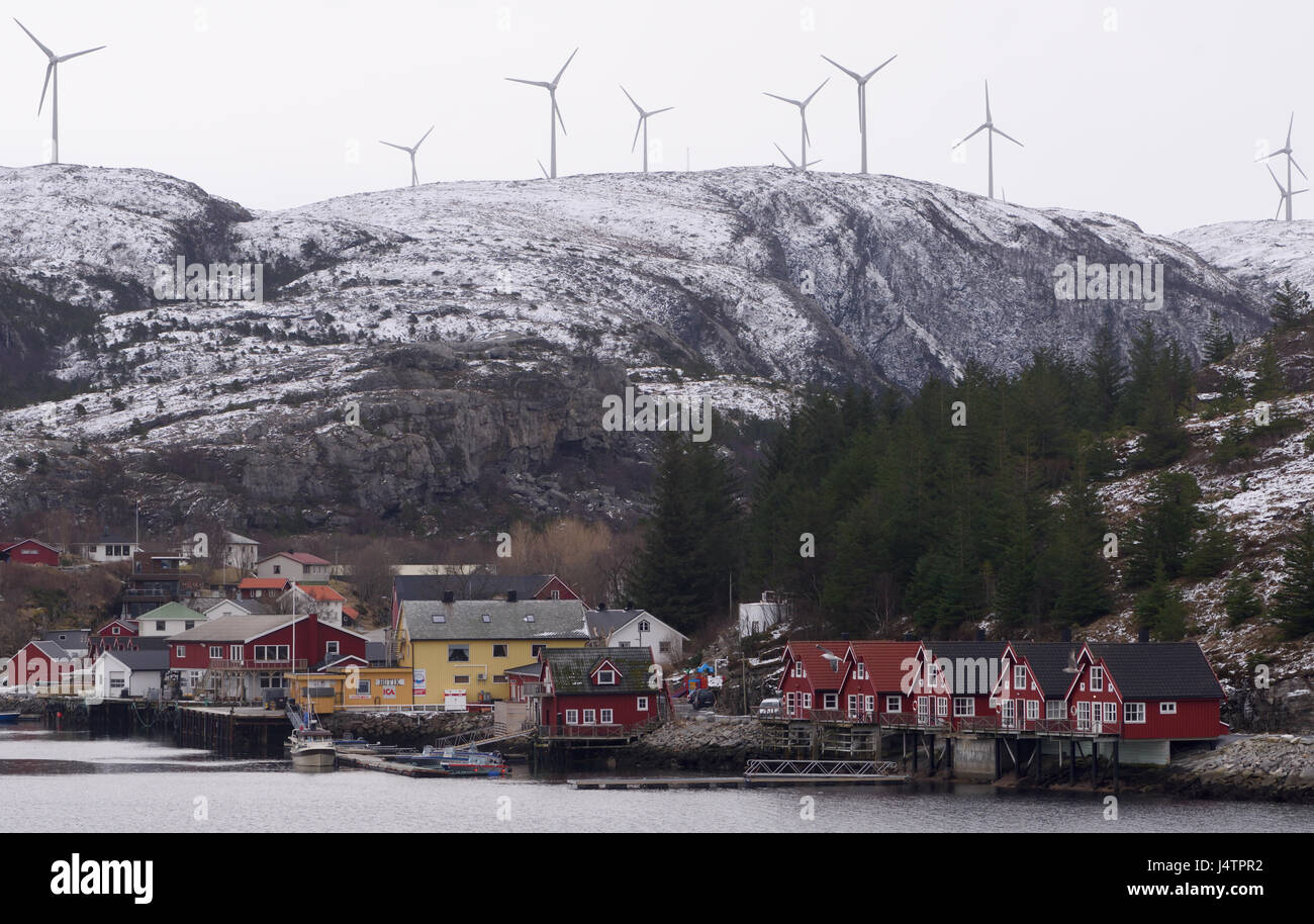 Sommerhäuser am Rande des Meeres im Dorf Bessaker, mit einem Windpark auf den Hügeln über. Bessaker, Sør-Trøndelag, Norwegen. Stockfoto