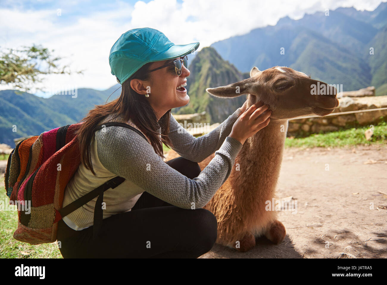 Touristischen Frau spielen mit Lama in Machu Picchu. Lächelnde Mädchen Touch Lama Tier Stockfoto