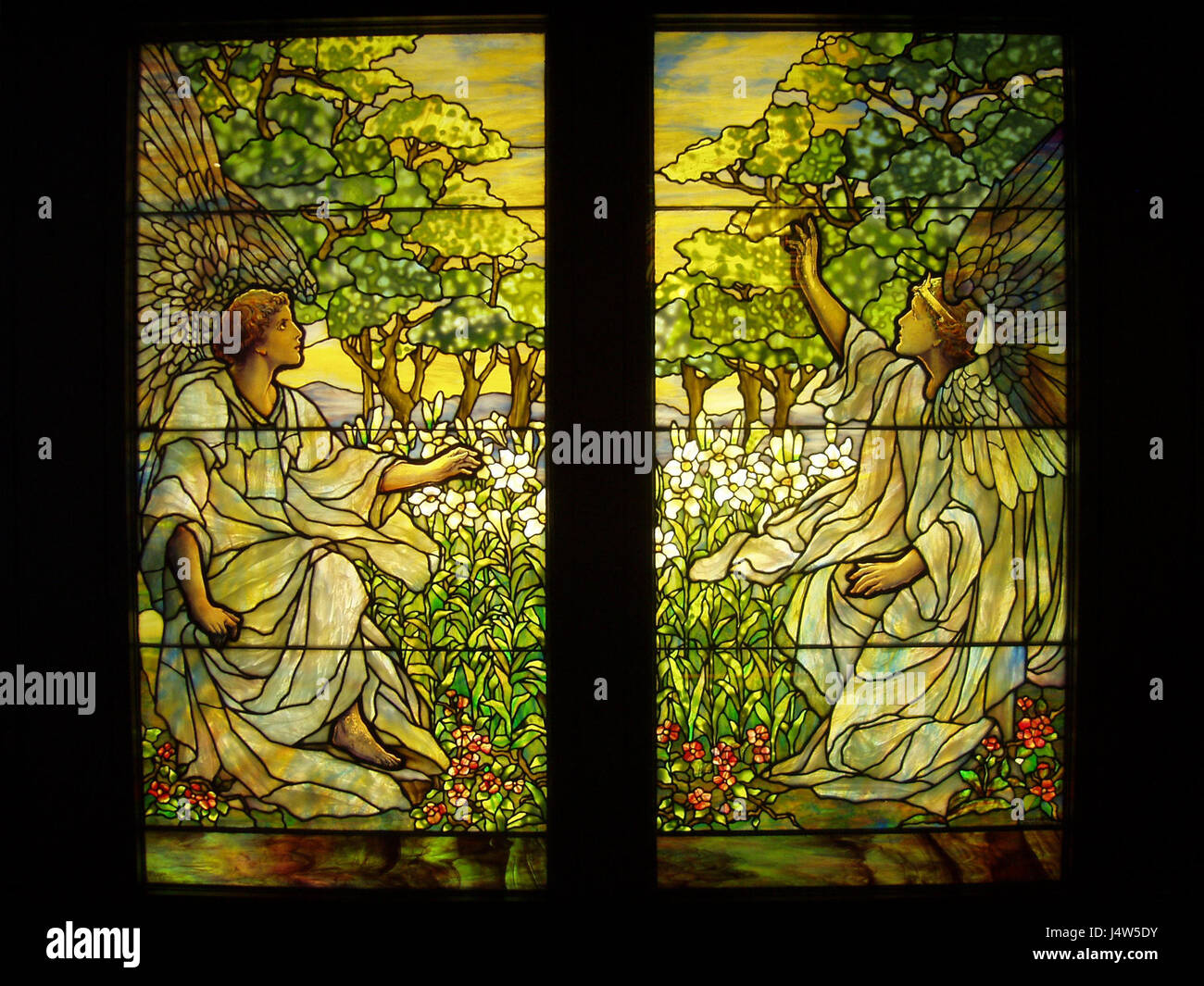 Diese Buntglasscheibe der Tiffany Studios wurde um 1910 geschaffen und zeigt zwei Engel in leuchtenden Farben. Das Stück veranschaulicht den Jugendstil und zeigt die Beherrschung der Glasmalerei des Studios. Stockfoto