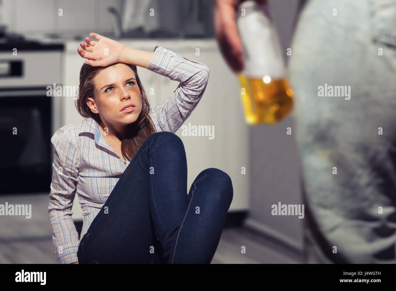 Frau Opfer von häuslicher Gewalt und Missbrauch. Frau Angst vor einem Mann mit einer Flasche in der Küche Stockfoto