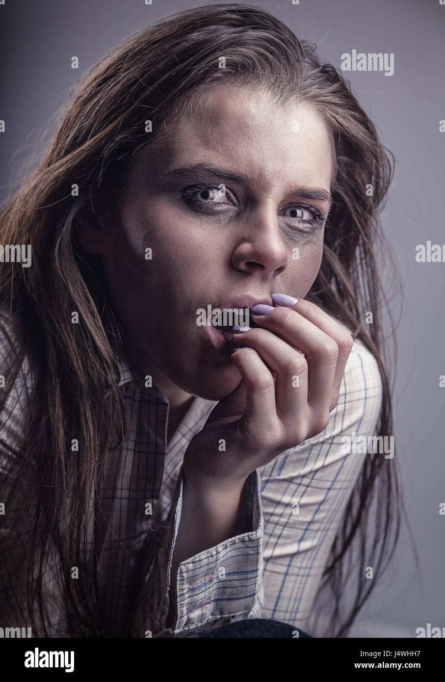 Verängstigte Mädchen mit Tränen in den Augen auf einem grauen Hintergrund Stockfoto