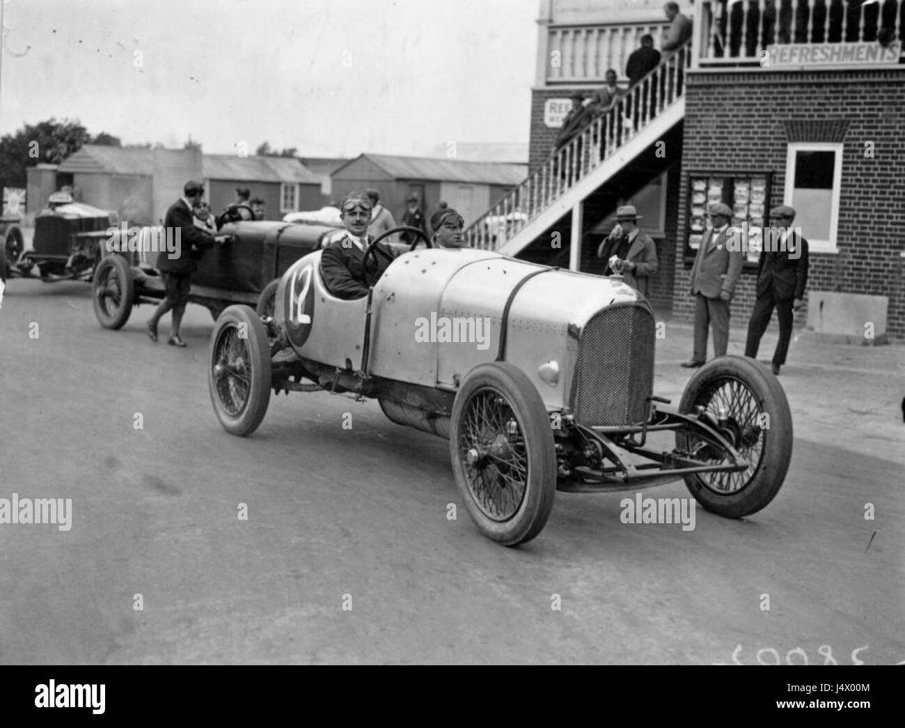 Dieses Foto zeigt W.G. Barlow, ein bemerkenswertes Individuum, das im August 1922 einen Bentley auf dem Brooklands Circuit fuhr. Brooklands war eine Pionierveranstaltung im Motorsport in Großbritannien, wo er frühe Rennveranstaltungen ausrichtete. Das Bild repräsentiert Motorsportgeschichte und Automobilkultur des frühen 20. Jahrhunderts. Stockfoto