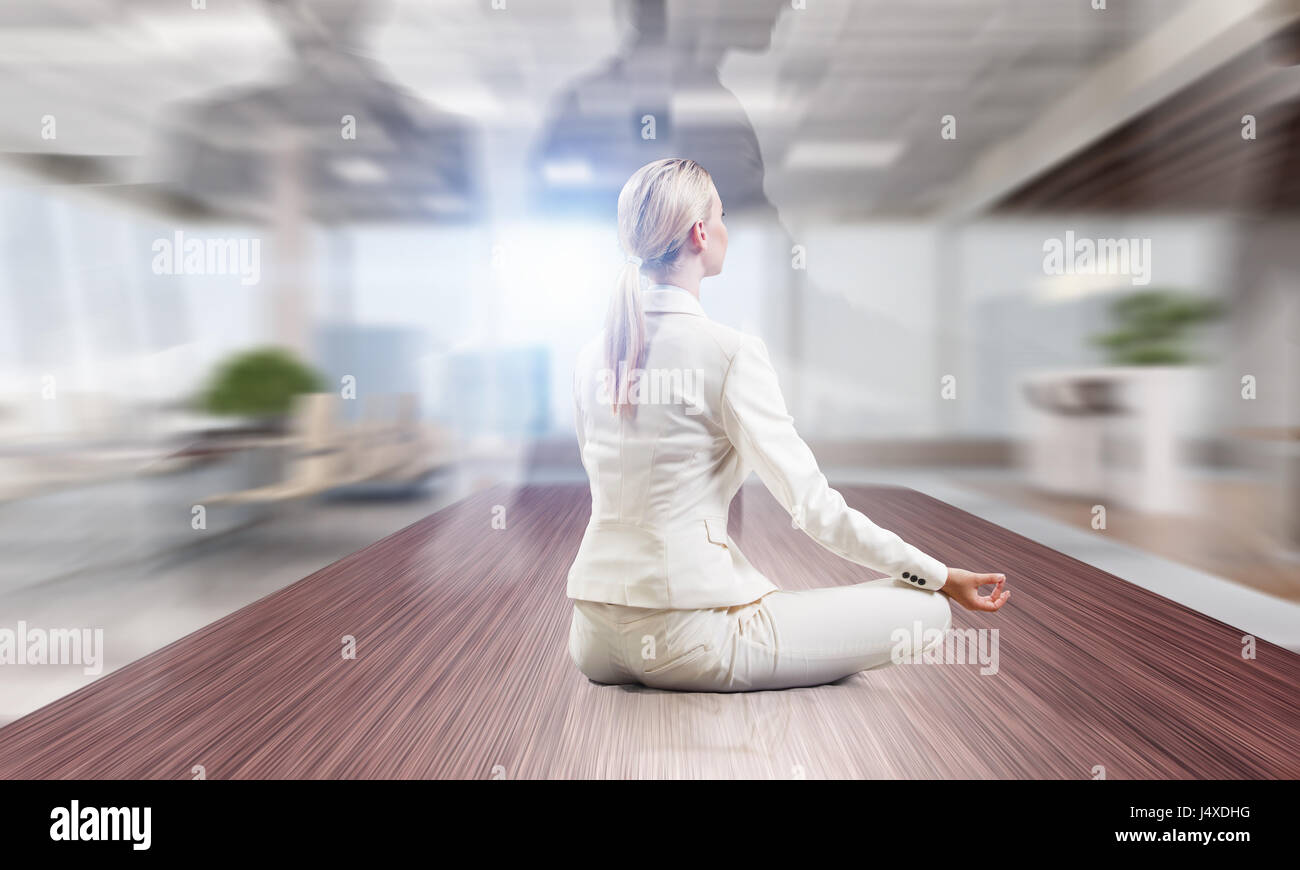 Junge attraktive Frau cross legged Lotus Yoga-Pose am Schreibtisch sitzen. Mixed-media Stockfoto