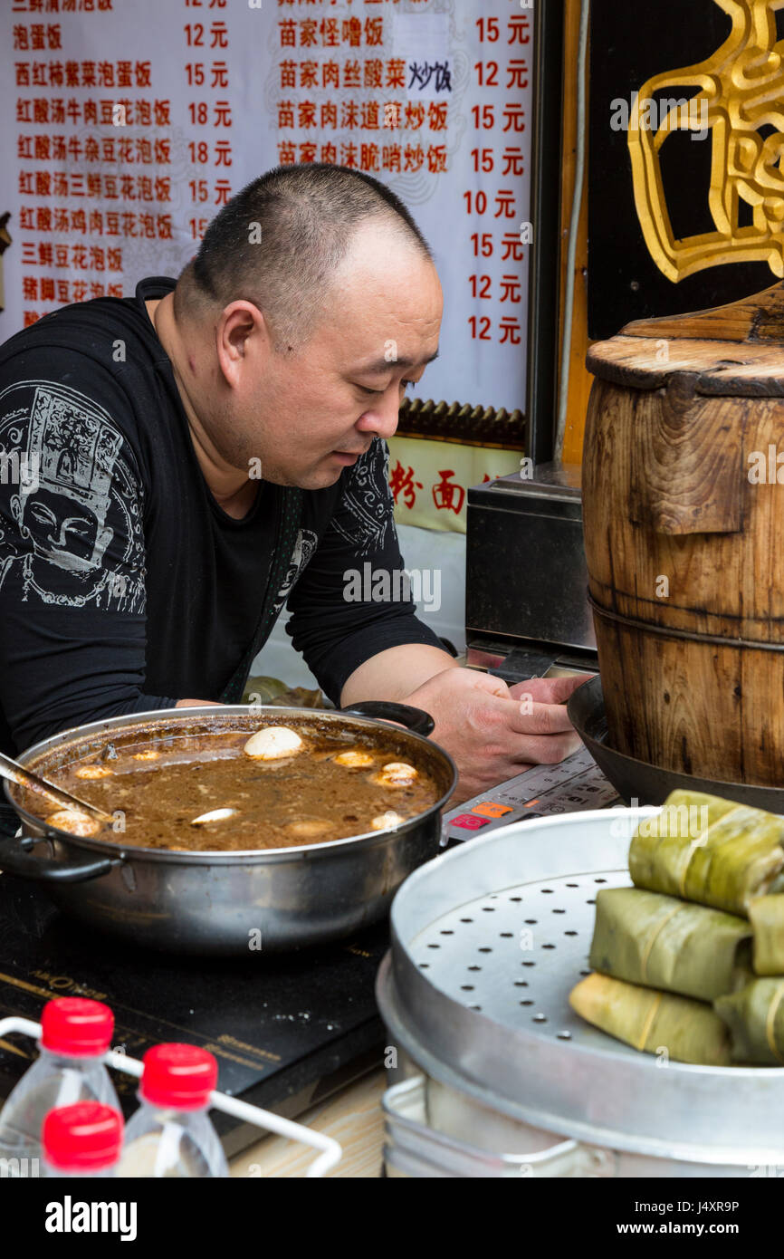 Zhenyuan, Guizhou, China.  Shop Verkauf Snack Food, Mann sein Handy überprüfen. Stockfoto