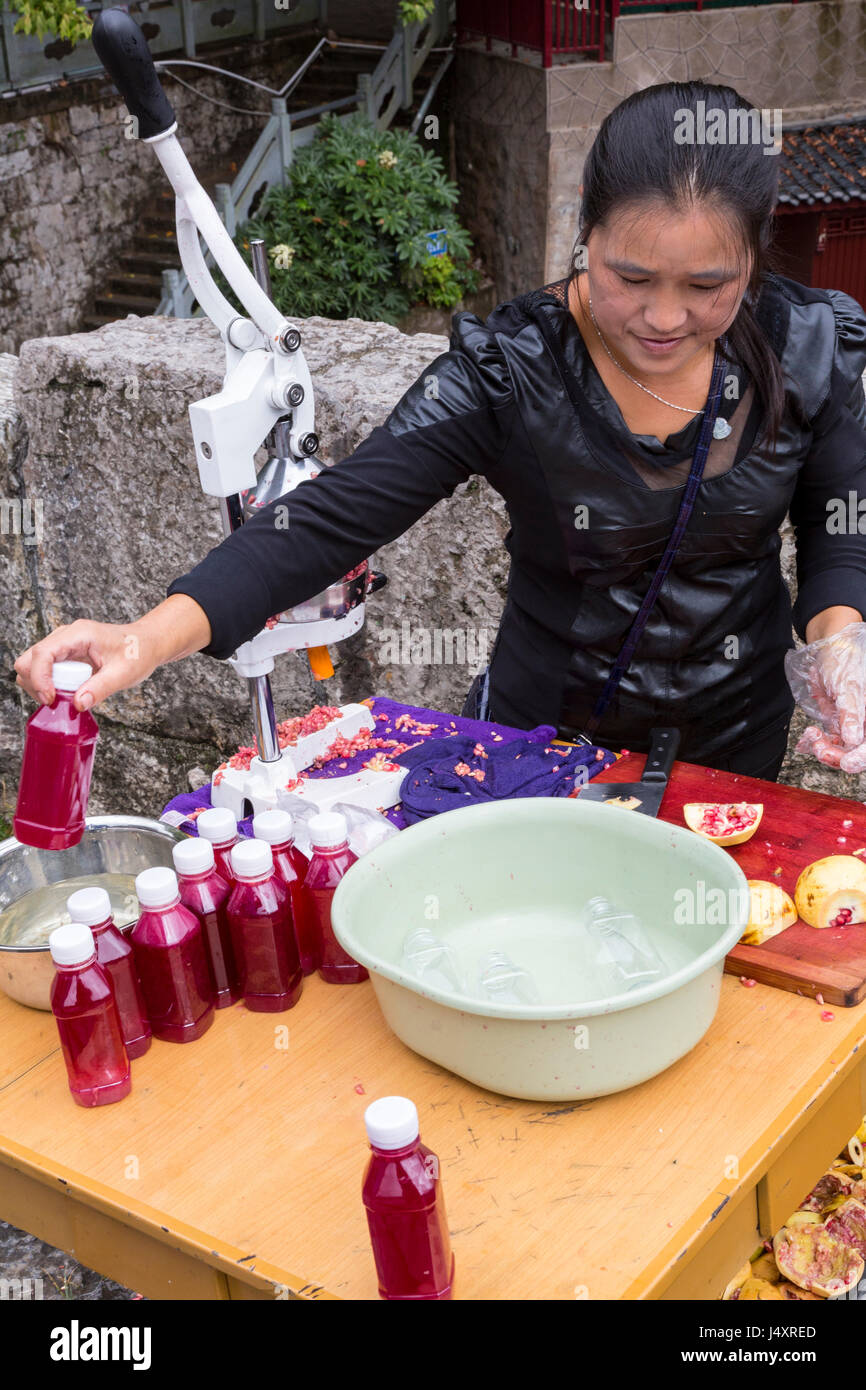 Zhenyuan, Guizhou, China.  Frau frisch gepressten Granatapfelsaft zu verkaufen.  Beachten Sie die Kunststoff-Handschuh Foir Hygiene. Stockfoto