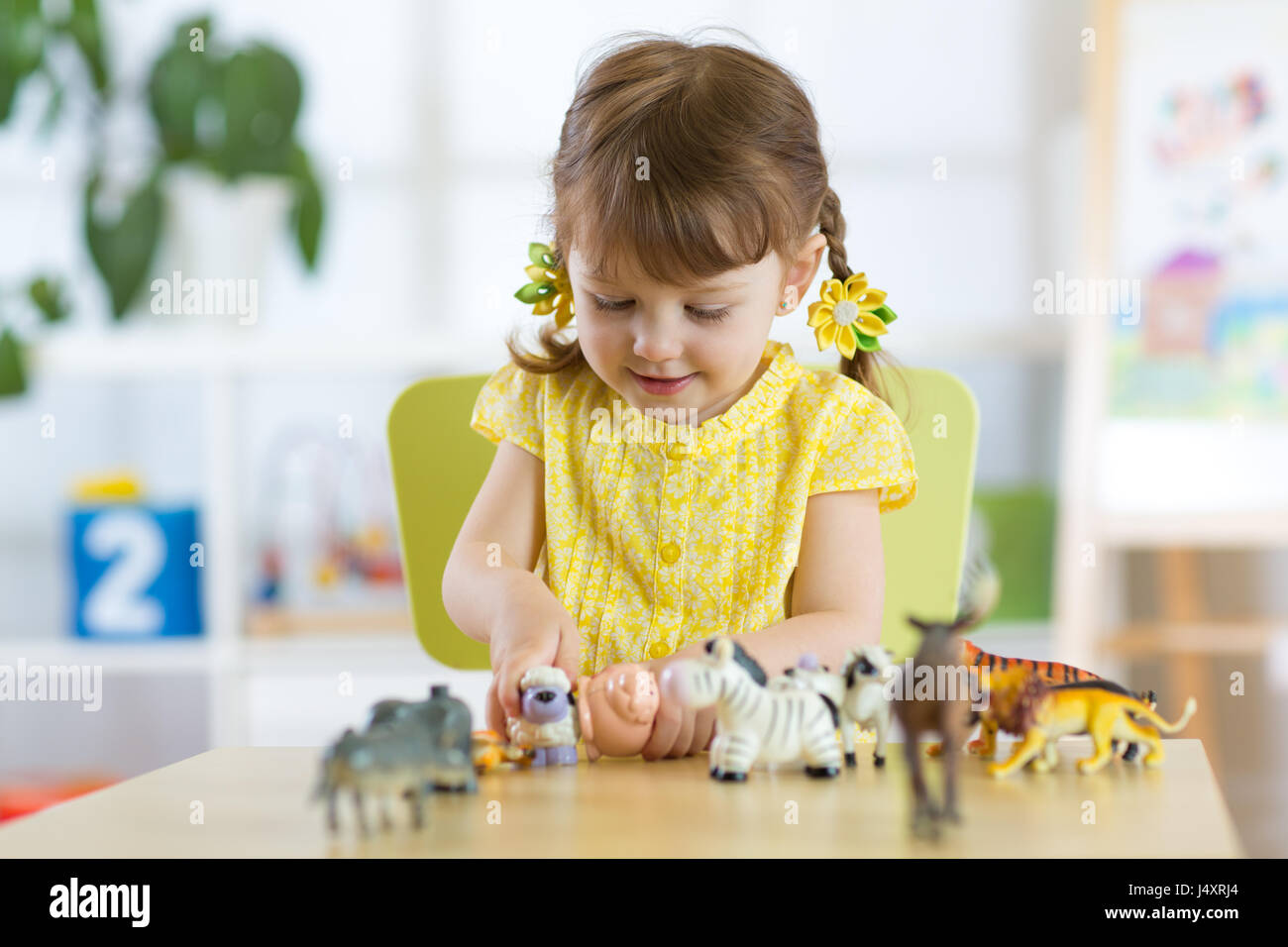 Glückliches kleines Kind spielt tierisches Spielzeug daheim oder Kindertagesstätten Stockfoto