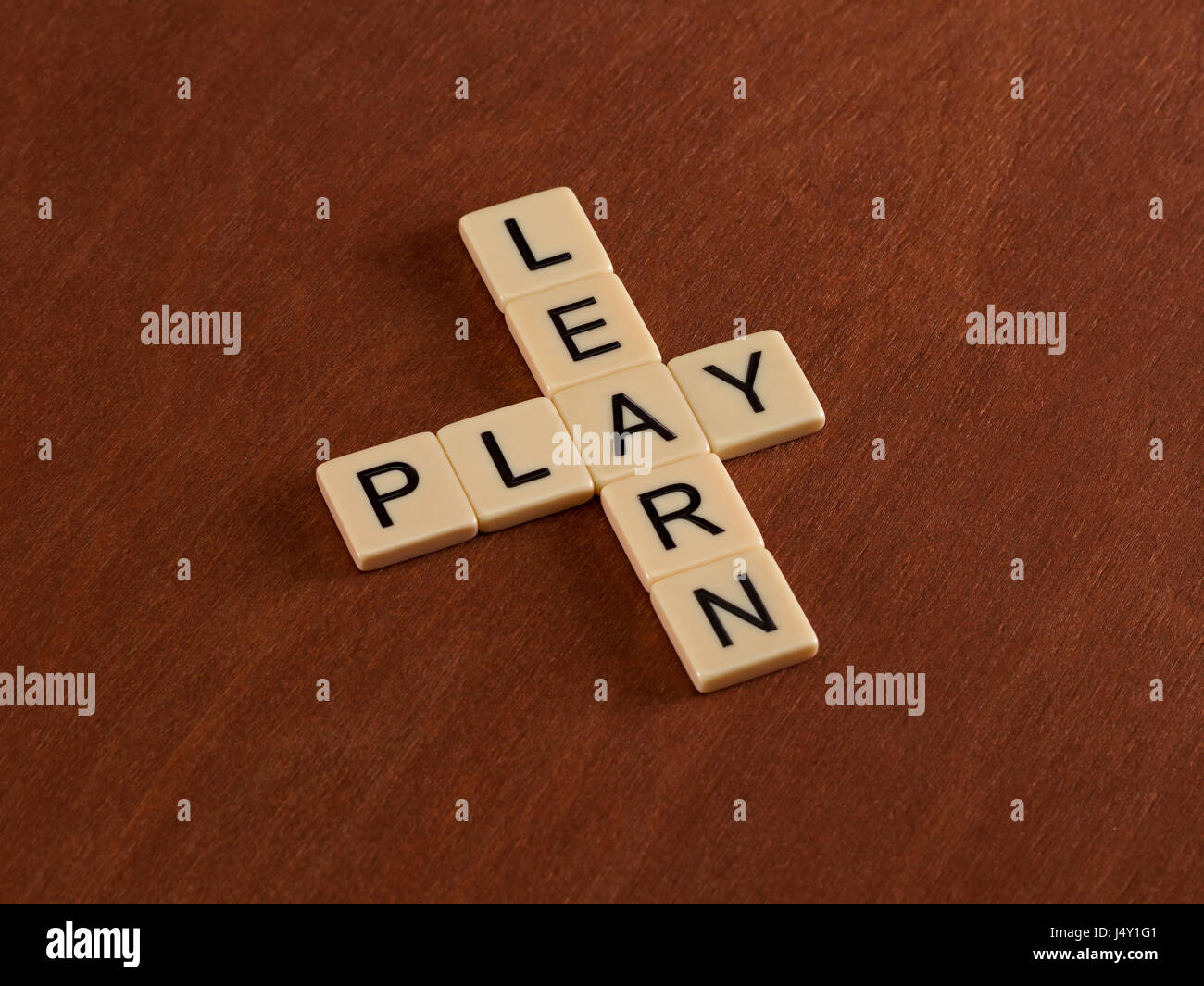 Kreuzworträtsel mit Worten lernen und spielen. Bildungskonzept. Elfenbein Fliesen mit Großbuchstaben auf Mahagoni Brett. Stockfoto