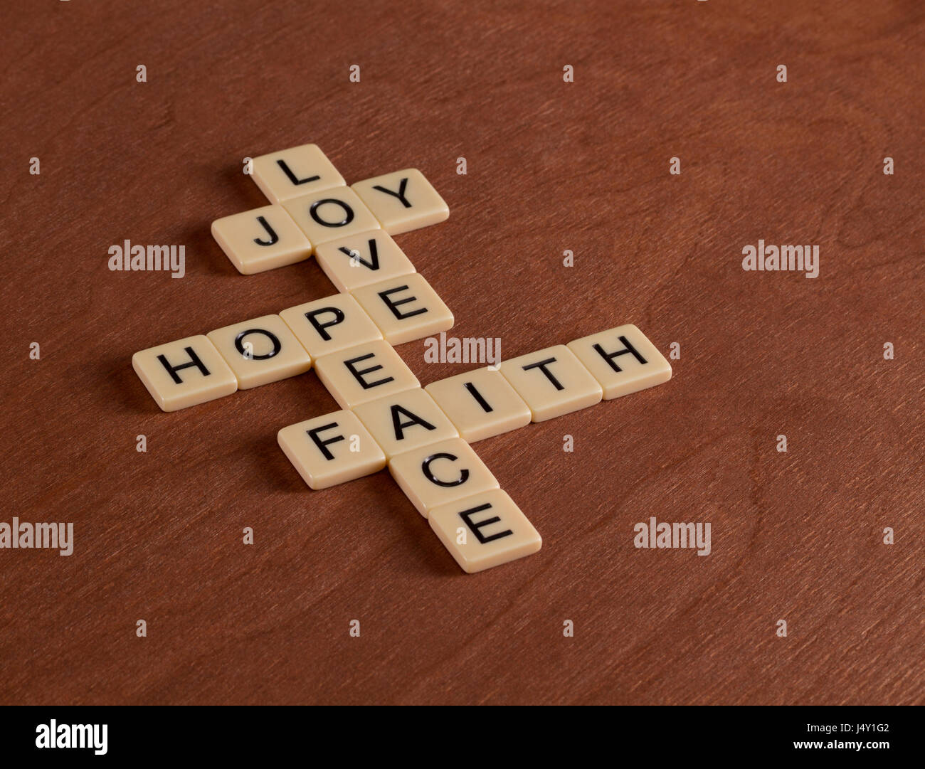 Kreuzworträtsel mit Worten glaube, Hoffnung, Liebe. Glaubens-Konzept. Elfenbein Fliesen mit Großbuchstaben auf Mahagoni Brett. Stockfoto