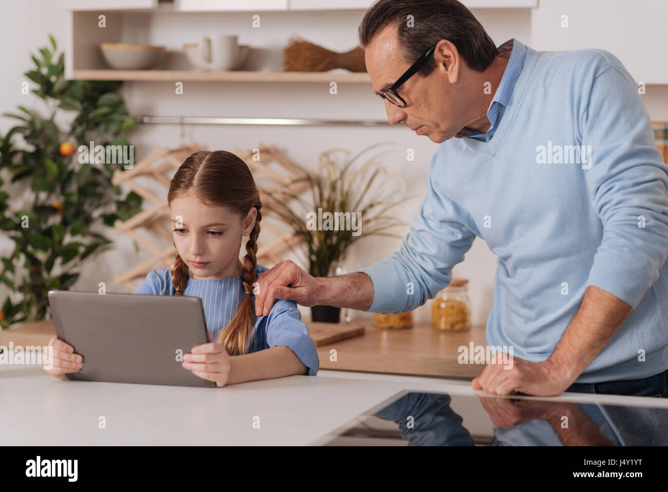 Fürsorglichen Großvater erzählt Enkelin Stop mit Gadget im Innenbereich Stockfoto