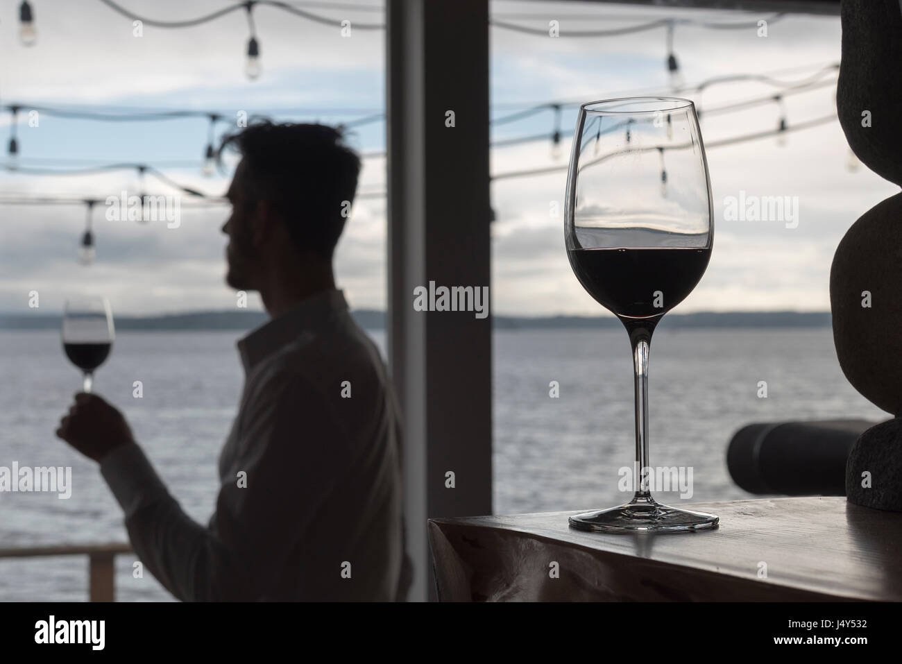 Held Wein Glas mit Mann im Silhouette stehen im Hintergrund durch Fenster mit Kristall-Gläsern Stockfoto