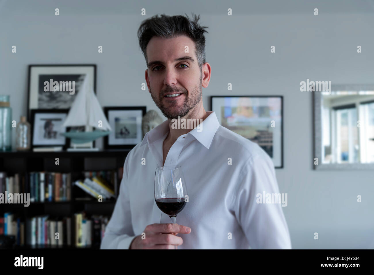 Gut aussehender Mann mit Rotwein in einem Strandhaus in natürlichem Licht Stockfoto