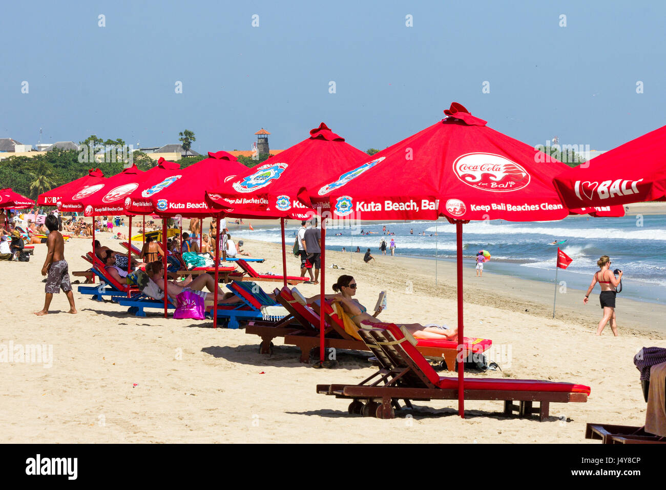 Menschen Sonnenbaden unter Sonnenschirmen an heißen, sonnigen Tag am Strand von Kuta, Bali, Indonesien Stockfoto