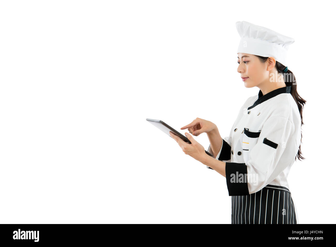 Profi-Koch auf der Suche im Online-Menü und zeigt Touch digital Tablet-Computer-Bildschirm auf weiße Wand Hintergrund isoliert. Stockfoto